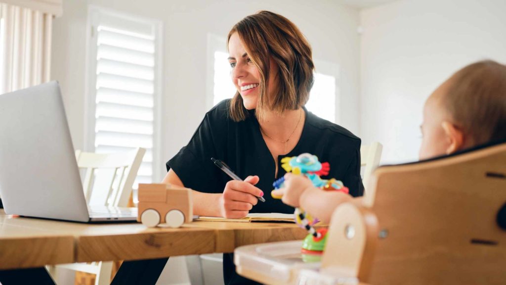 Work life balance with woman working on computer with a baby