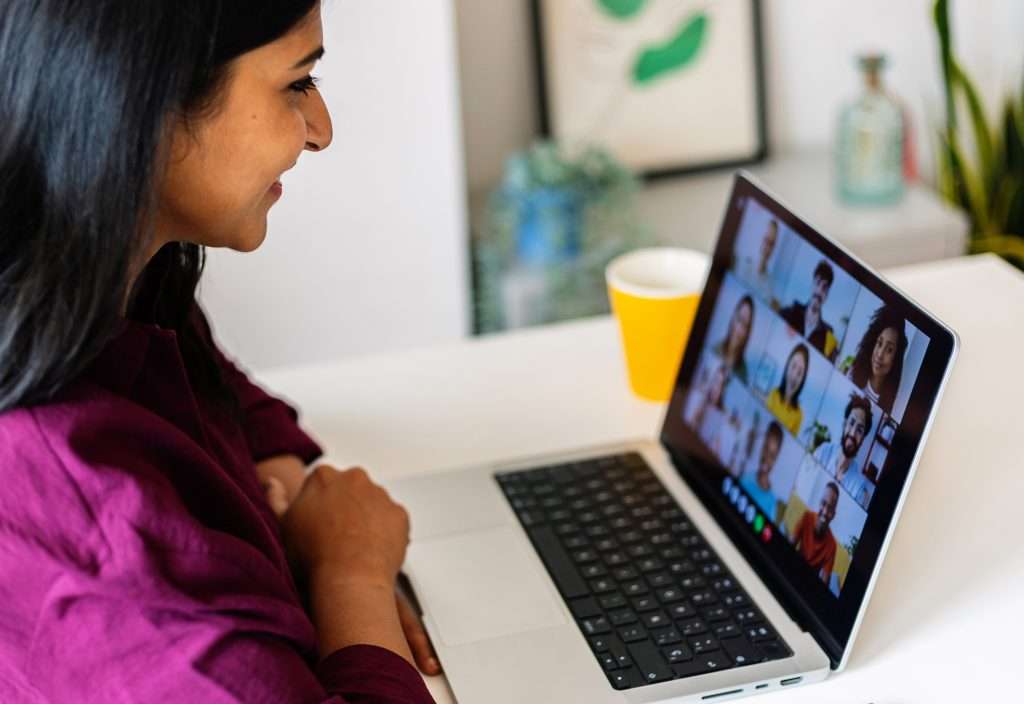 Young indian businesswoman working on laptop in the office, having a video call with colleagues. Teamwork and businesspeople concept.