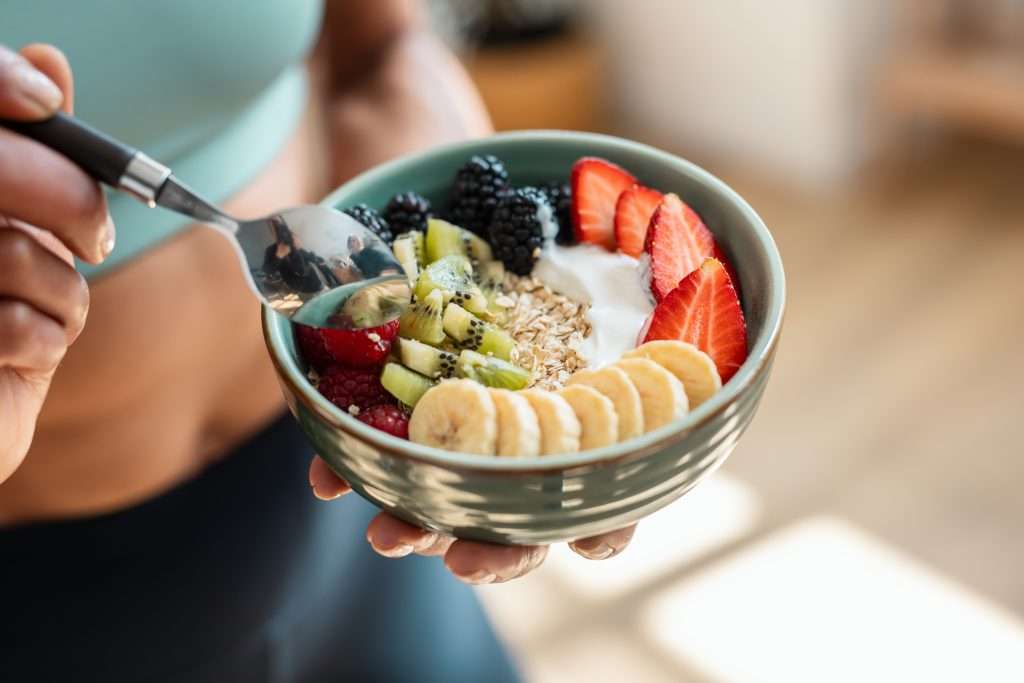 Close,Up,Of,Athletic,Woman,Eating,A,Healthy,Fruit,Bowl